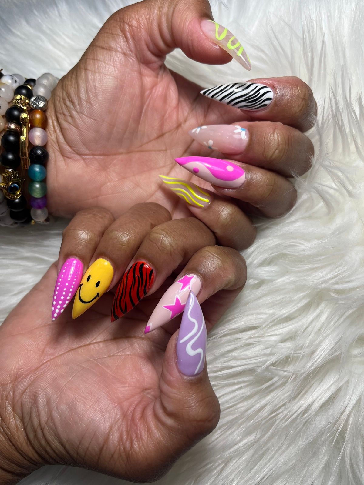 Mismatched stiletto nails with smiley faces, zebra print, stars and swirls