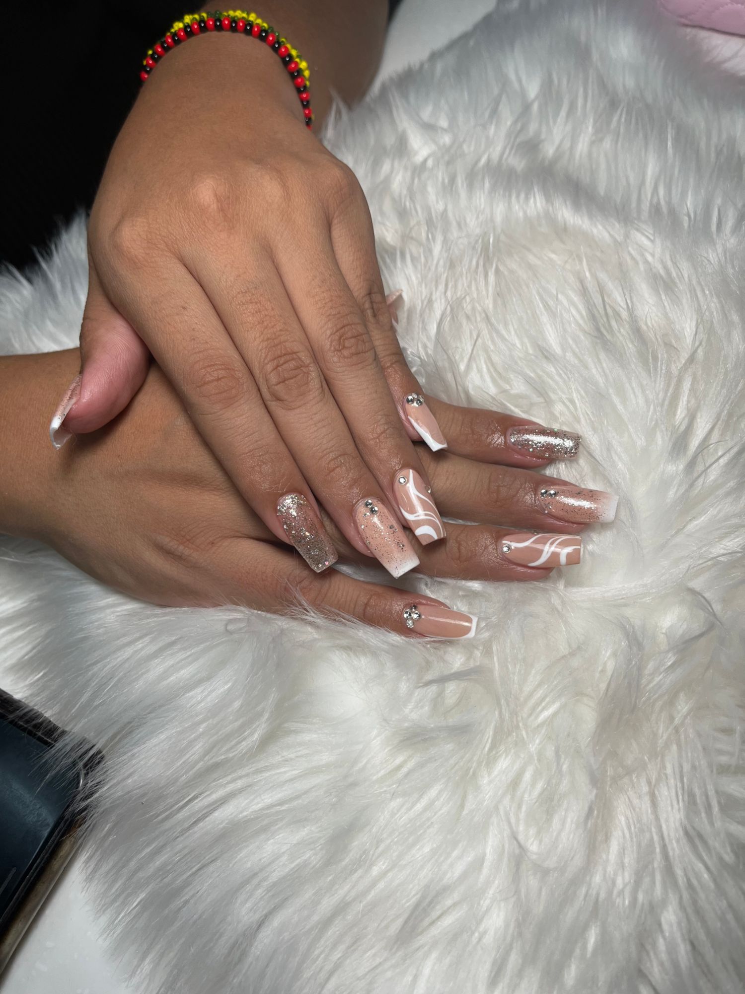 Nude coffin nails with white swirl French tips, silver glitter and rhinestones