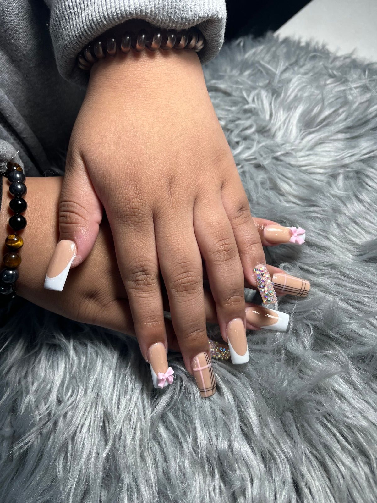 Nude square nails with white French tips, pink 3D bows and a glitter accent